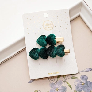 Detalle de pinzas para el cabello en forma de corazón de terciopelo verde oscuro