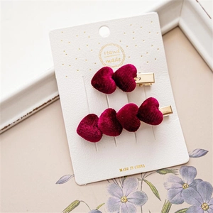 Detalle de pinzas de pelo de corazón en terciopelo rojo con base dorada