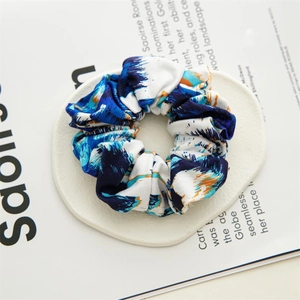 Gros plan détaillé du chouchou en coton tie-dye bleu avec des plis doux et élastiques