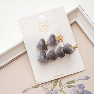 Vista macro detallada de dos pinzas para el cabello de terciopelo gris con forma de corazón