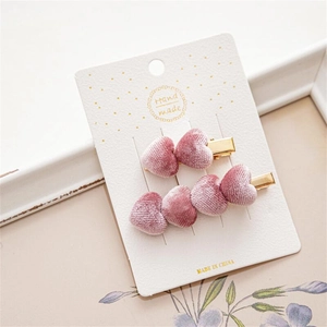 Detalle de pinzas para el pelo de terciopelo rosa en tarjeta de presentación artesanal