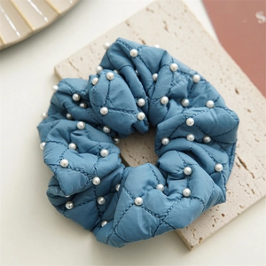 Detail of blue quilted scrunchie with white pearls and luxury diamond stitch pattern