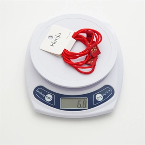 Detail of red elastic hair bands with golden festive tags showing weight on scale