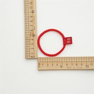 Close-up measurement of a red braided hair tie showing a 5cm diameter with gold lettering