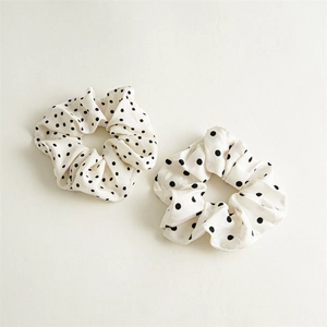Gros plan de chouchous en satin blanc à pois noirs avec détails de texture du tissu doux