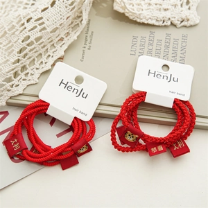 Close-up of red braided elastic hair bands with golden tiger pattern and lucky charms