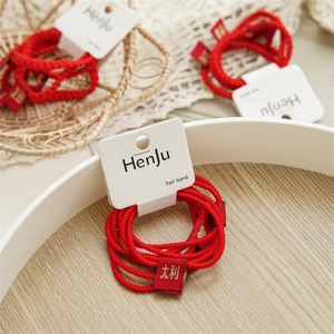 Detail of red elastic hair bands with festive woven labels on a wooden background