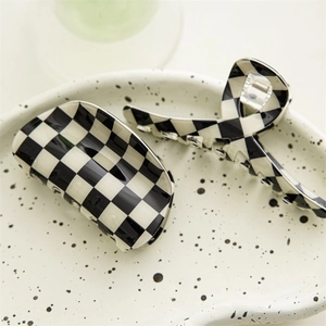 Detail of checkered hair claws with black and white plaid pattern on ceramic tray