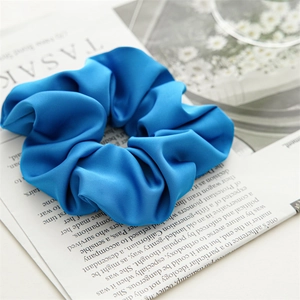 Detailed view of large blue satin hair scrunchie with soft sheen and textured fabric