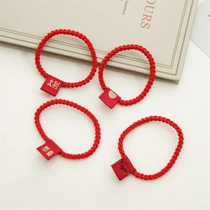 Detail view of 4 red braided hair ties with Chinese characters and Tiger motifs