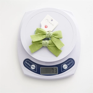 Close-up of green bow hair ties showing striped fabric texture on a digital scale