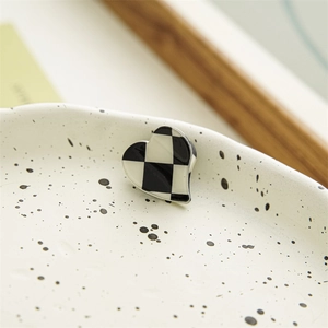 Detailed close-up of heart-shaped checkerboard hair claw with black and white enamel finish