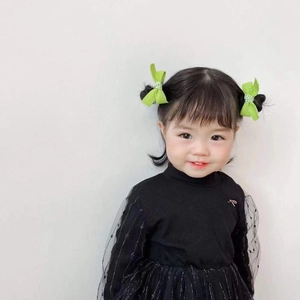Close-up of girl wearing a bright green bow hair clip with a black polka dot tulle dress