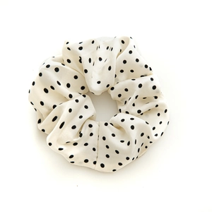 Chouchou élégant en satin blanc avec pois noirs classiques sur un fond blanc neutre