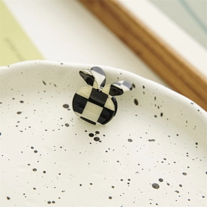 Detail of a rabbit-shaped hair claw clip with black and white checkerboard pattern texture