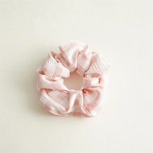 Detail eines rosa-weißen Haargummis mit Karomuster und elastischer Seersucker-Struktur