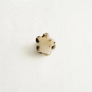 Détail d'une mini pince à cheveux fleurie avec motif écaille sur fond beige neutre