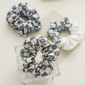 Close-up of three checkered fabric scrunchies with floral patterns and soft cotton texture