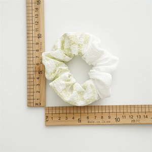 Détail d'un chouchou floral blanc avec mesure de la taille à 9,5 cm de diamètre