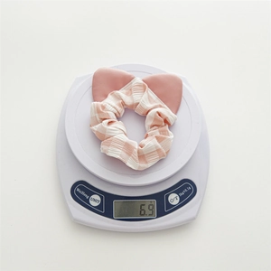 Dettaglio dell'elastico per capelli a scacchi rosa con orecchie pesante 6,9g su bilancia