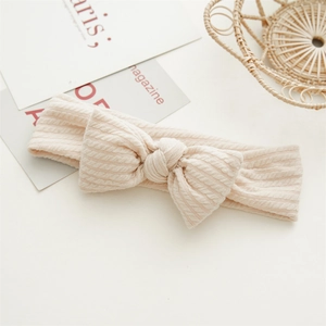 Détail du bandeau tricoté pour bébé avec grand nœud en tissu extensible beige
