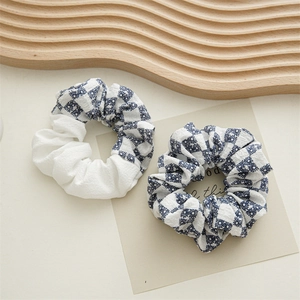 Detailed view of floral daisy and plaid gingham fabric scrunchies in blue and white
