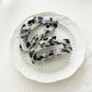 Detail of square marble acrylic hair claws in black and white spotted patterns