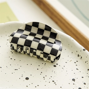 Detailed top view of a black and white checkerboard hair claw clip on a ceramic tray