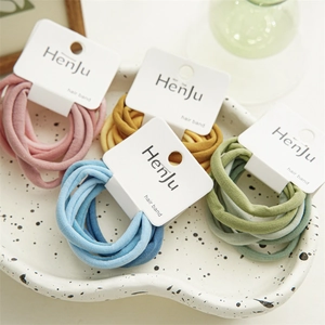Élastiques à cheveux spirales pastel rose, jaune, bleu et vert présentés sur un plateau
