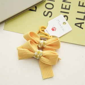 Detail of yellow bow hair ties made of ribbed ribbon with checkered fabric centers