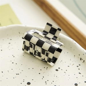 Detail view of square black and white checkerboard hair claw clip on ceramic tray