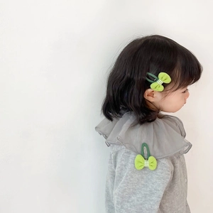 Close-up of mint green fabric bow hair clip with checkered center on a little girl