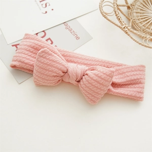 Vue détaillée du bandeau pour bébé en maille rose avec un grand nœud décoratif sur blanc