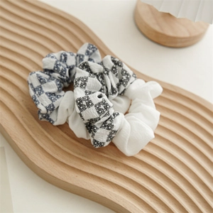 Close-up of checkered fabric hair scrunchies with floral patterns on a wooden tray