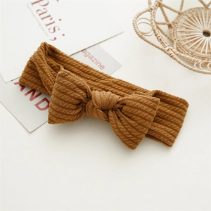 Gros plan d'un bandeau en tricot marron pour bébé avec un nœud doux et texturé