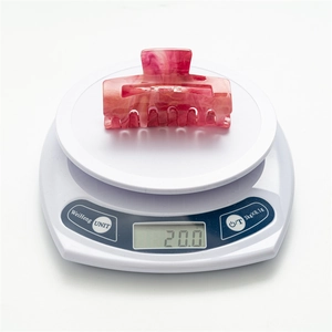 Detail shot of the pink marble hair claw clip on a scale weighing exactly 20.0 grams