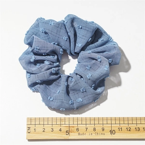 Detailed view of a blue seersucker hair scrunchie with 10cm diameter pom-pom texture