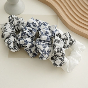 Three-piece set of plaid and plain seersucker scrunchies on a wooden board