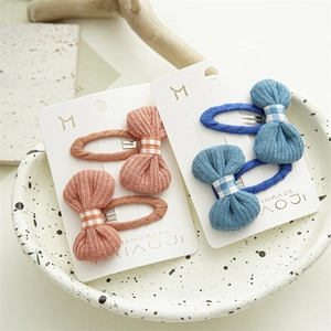 Detail view of two pairs of knit bow hair clips in orange and blue on a display card