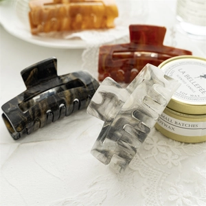 Detail showing four marble acetate hair claws with rectangular design and luxury stone patterns