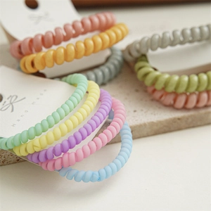Détail macro d'élastiques à cheveux spirales mats colorés sur carte fait main