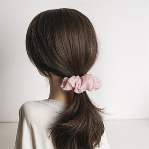 Detail of pink seersucker scrunchie with jacquard texture on low ponytail hairstyle