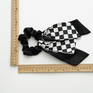 Flat lay of black hair scrunchie with checkered bow showing length of 20cm with a ruler