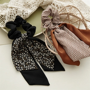 Dettaglio di scrunchies floreali vintage con nastri lunghi in raso nero e marrone