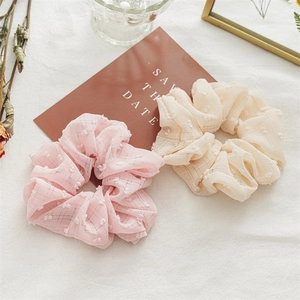 Detail of pink and beige seersucker scrunchies with polka dot texture on linen