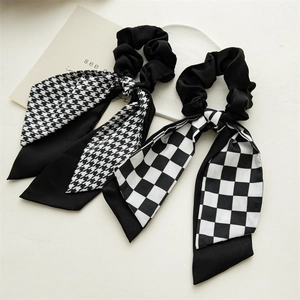 Close-up of black and white houndstooth and checkerboard scrunchies with long ribbons