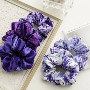 Dettaglio di quattro elastici scrunchie in raso viola con stampe stellate e marmo