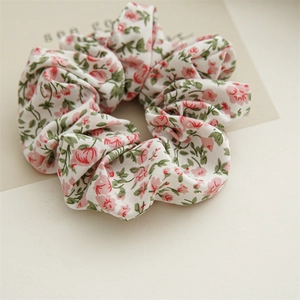 Dettaglio scrunchie in chiffon a fiori con piccoli fiori rossi e foglie verdi vivaci