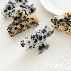 Detailed close-up of square acrylic claw clips with leopard and marble patterns