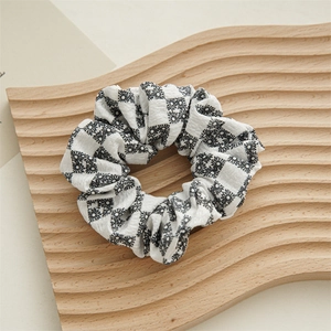 Detailed close-up of a black and white checkered daisy pattern fabric hair scrunchie